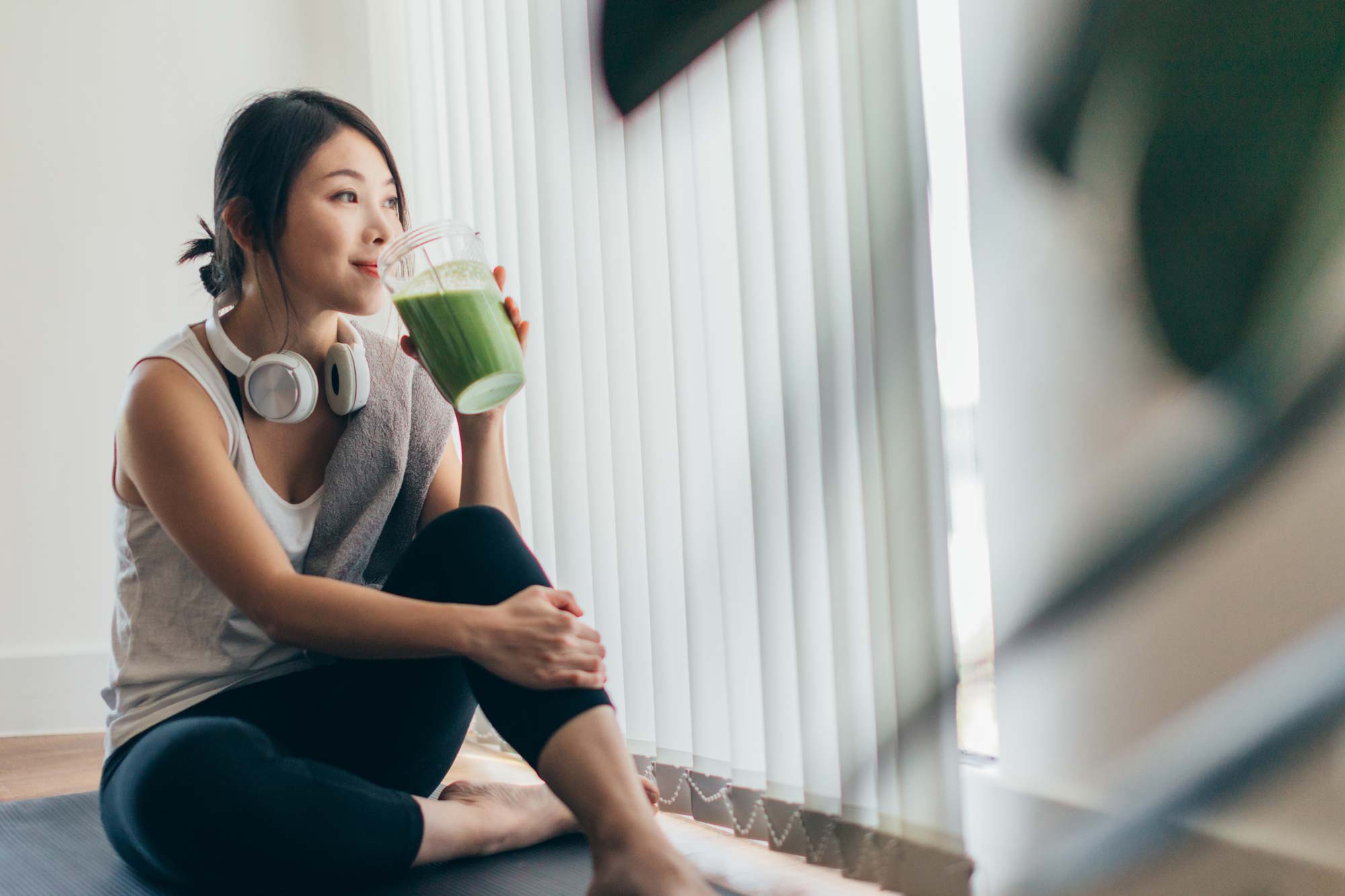 Kvinna på en yogamatta som dricker smoothie